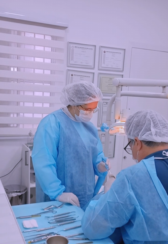 Equipe odontológica em procedimento cirúrgico de implante dentário com biossegurança na clínica do Dr. Rogério Fellinger